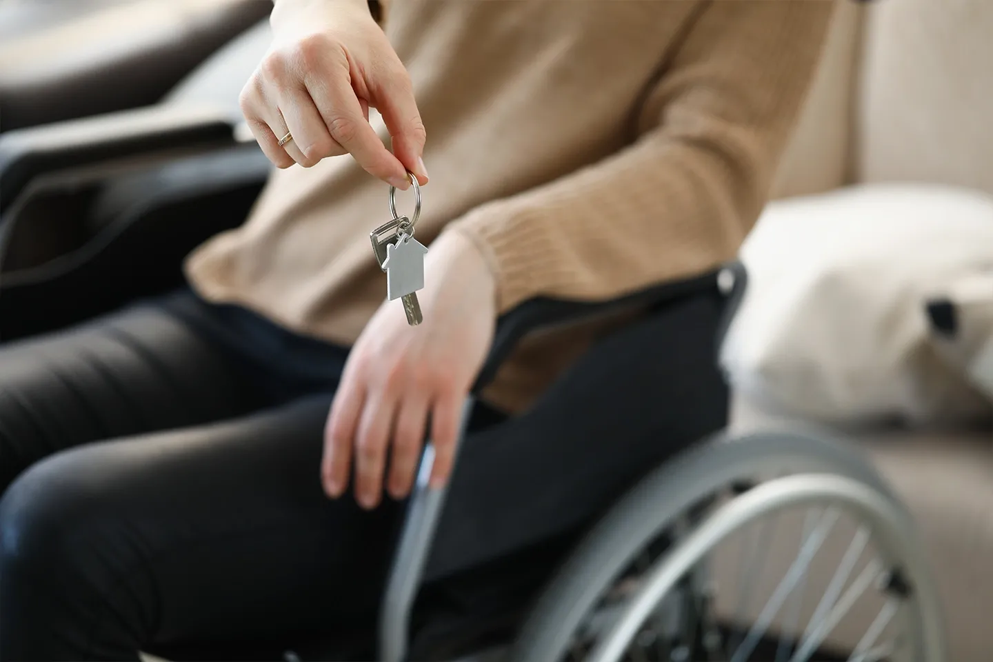 Woman in wheelchair holds keys to apartment.
