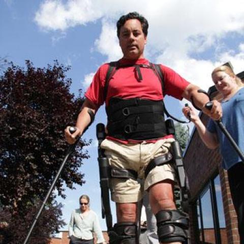 man wearing exso walking mechanism accompanied by a staffing nurse