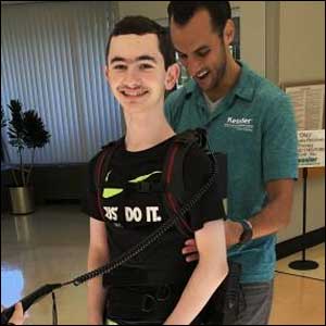 Teenager with a robotic walking device on him surrounding his body
