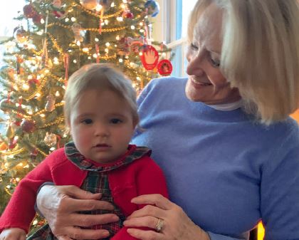 Pastora Goldner holding a baby in front of a christmas tree