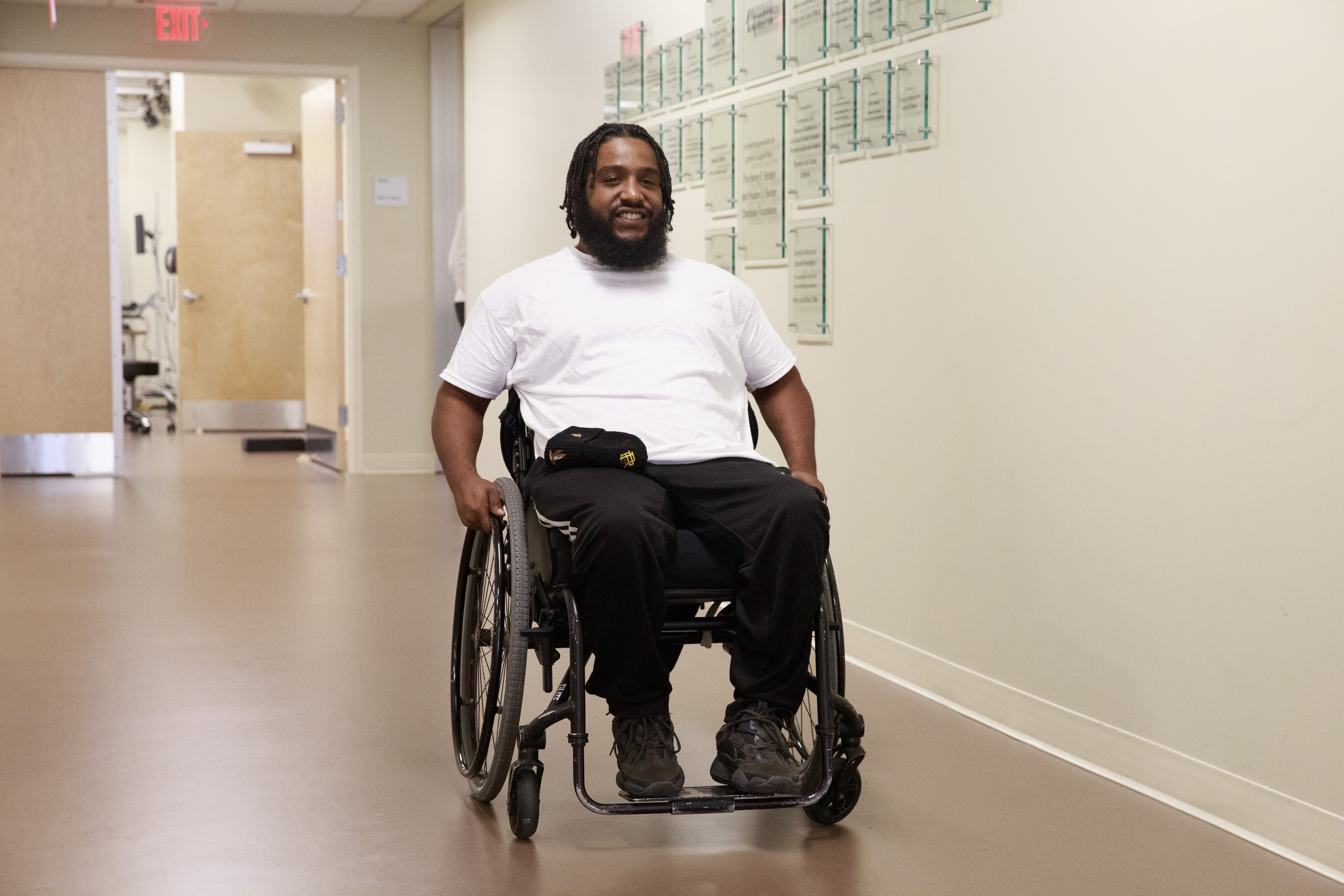 Man using a wheelchair sits in a long hallway