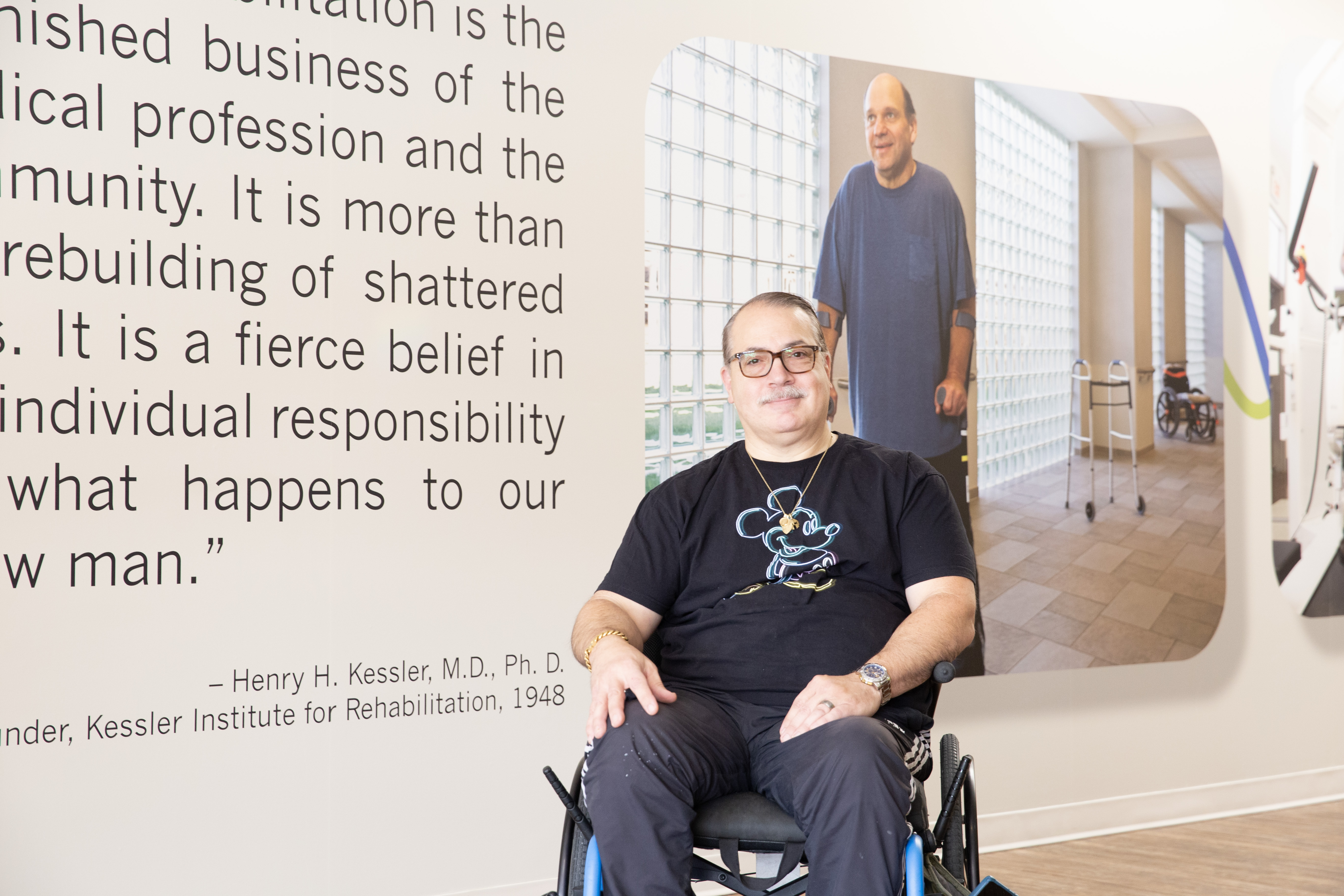 Man using a wheelchair sits in front of a mural