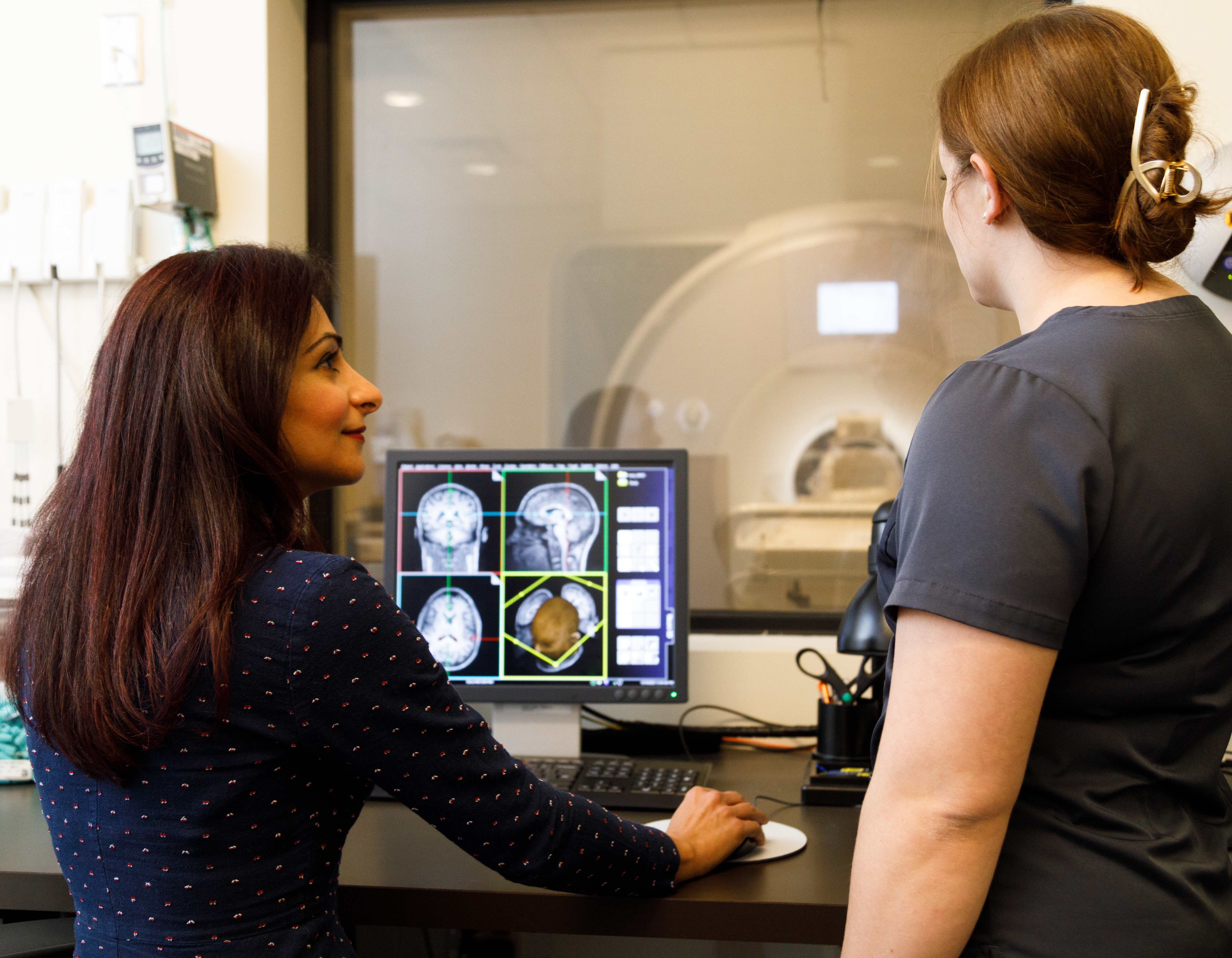 Two women stand in and MRI control room