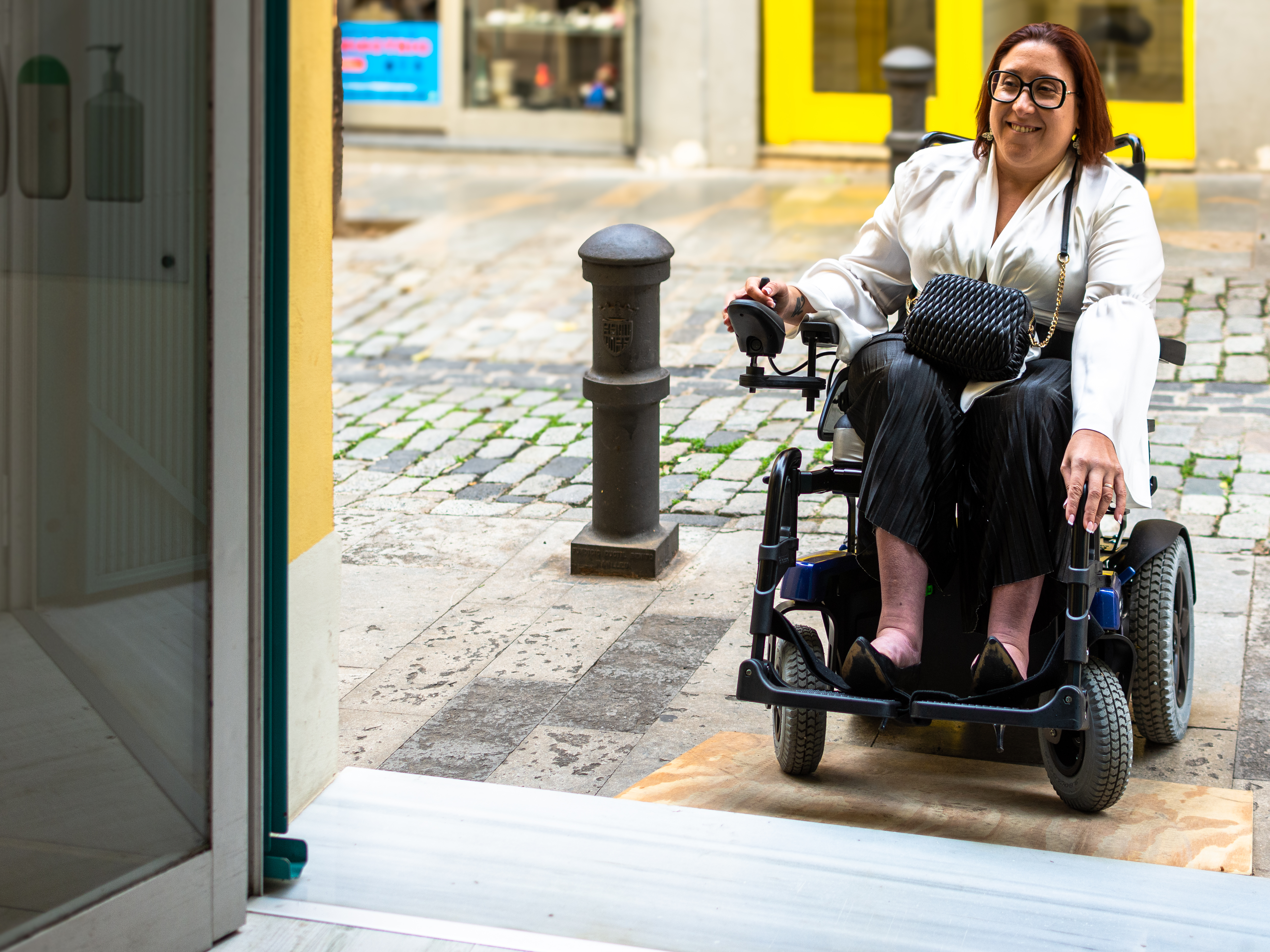 A women using a power wheelchair using the ramp to get on a public bus