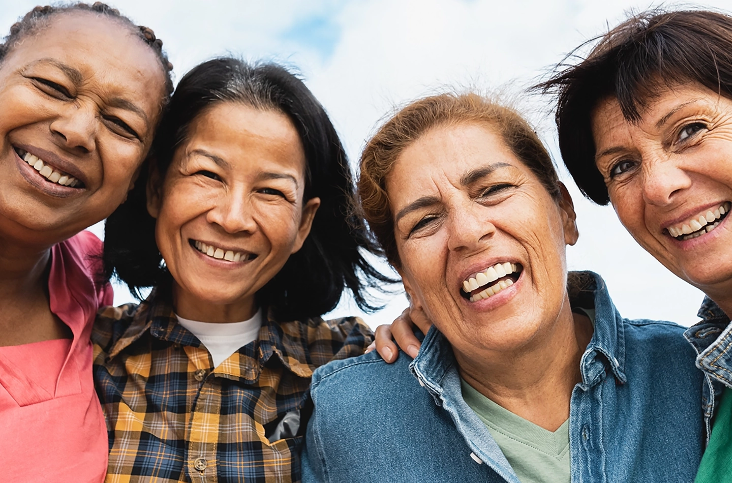 4 woman smiling for the camera with their arms around each other