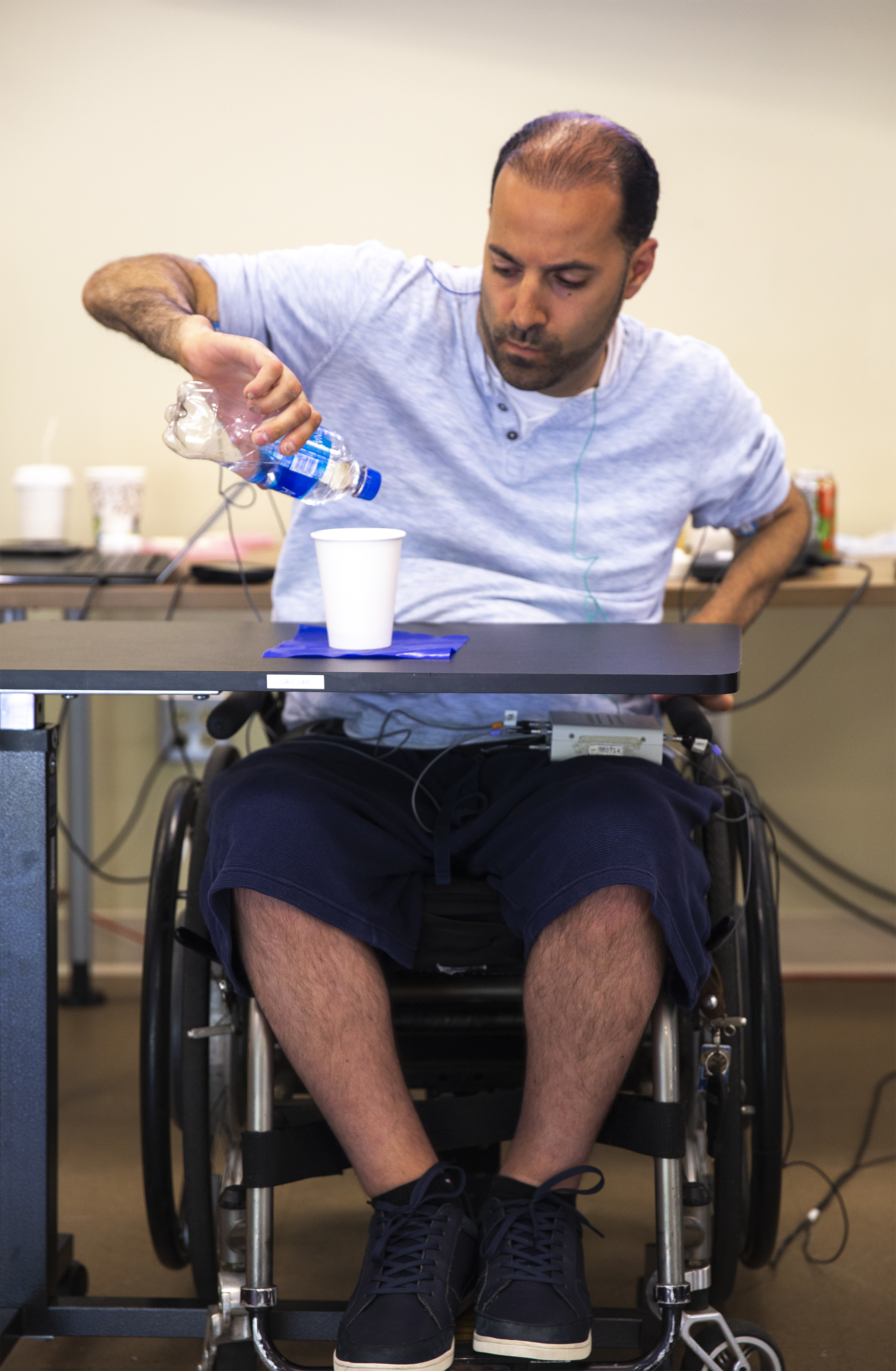Man is pouring water into a cup after receiving spinal stimulation.
