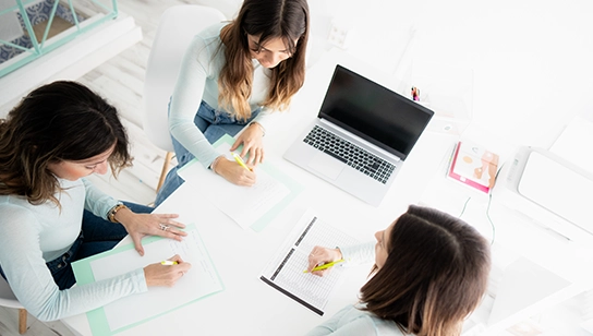 A group sits and works together at a conference table. 