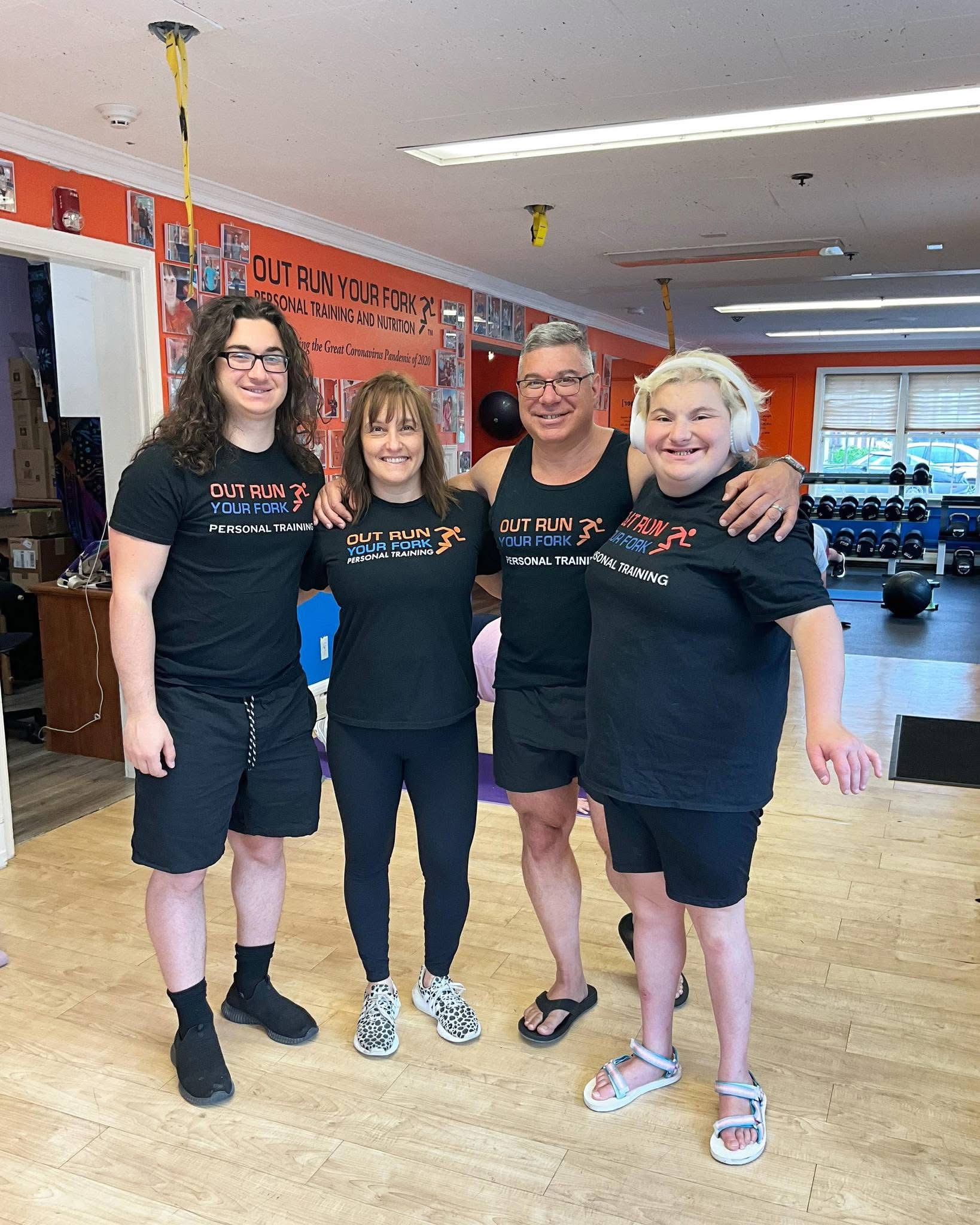 Family of four smile together for a photo in a fitness environment