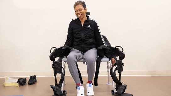 Woman sits on a bench with a robotic exoskeleton