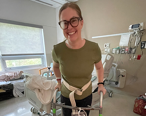 Female TBI participant standing with walker in hospital room