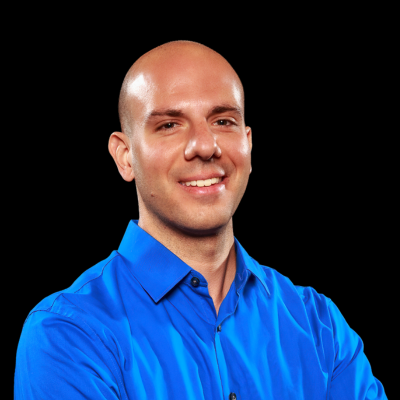 Headshot of Chris Cagna, PhD. The background is black and he is wearing a blue button up top.  has context menu