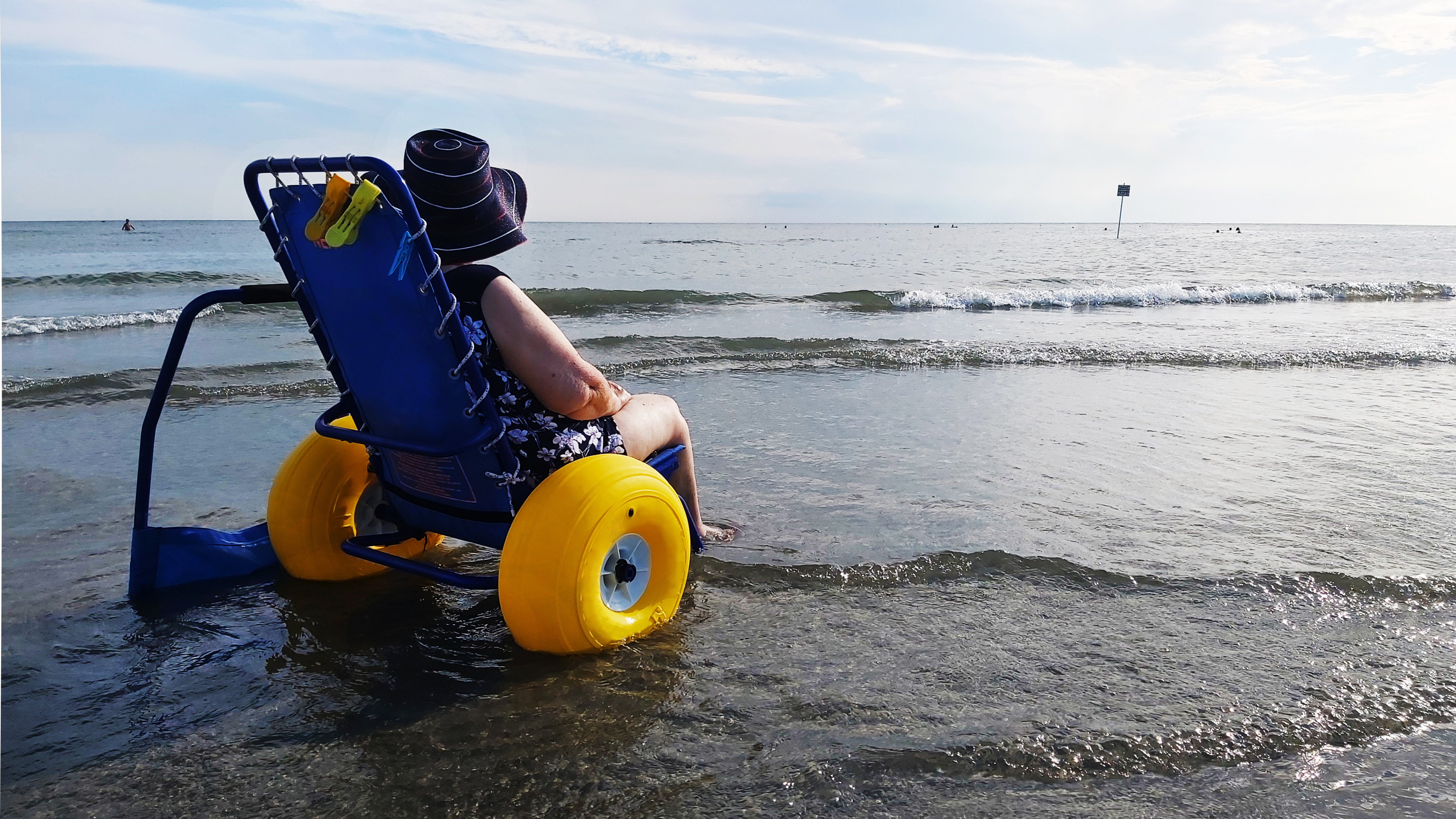 Image of a person in an accessible beach chair sitting in the water.