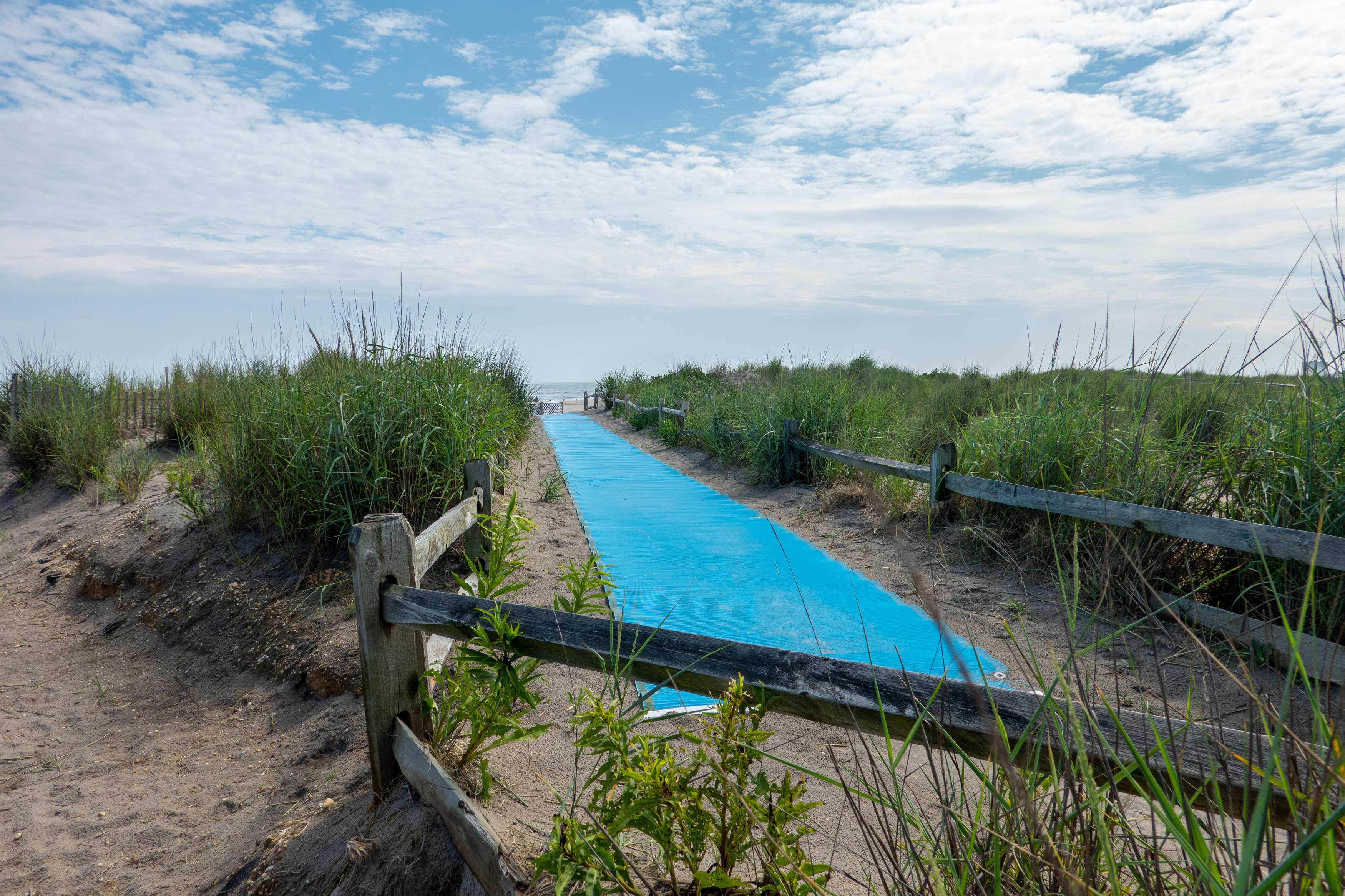 Image of a blue accessible beach mat in between dunes.