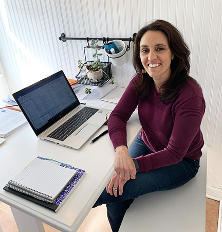 Amanda Botticello, smiling and sitting next to her computer