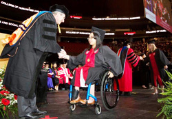 woman in a wheelchair accepting diploma from a man 