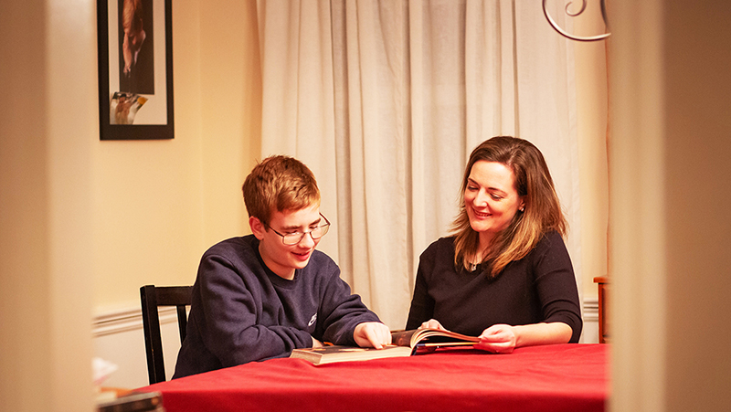 Dr. Helen Genova sitting at a table, homeschooling her son