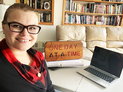 Holly Klecha, sitting next to a computer and craved block with inspirational quote 