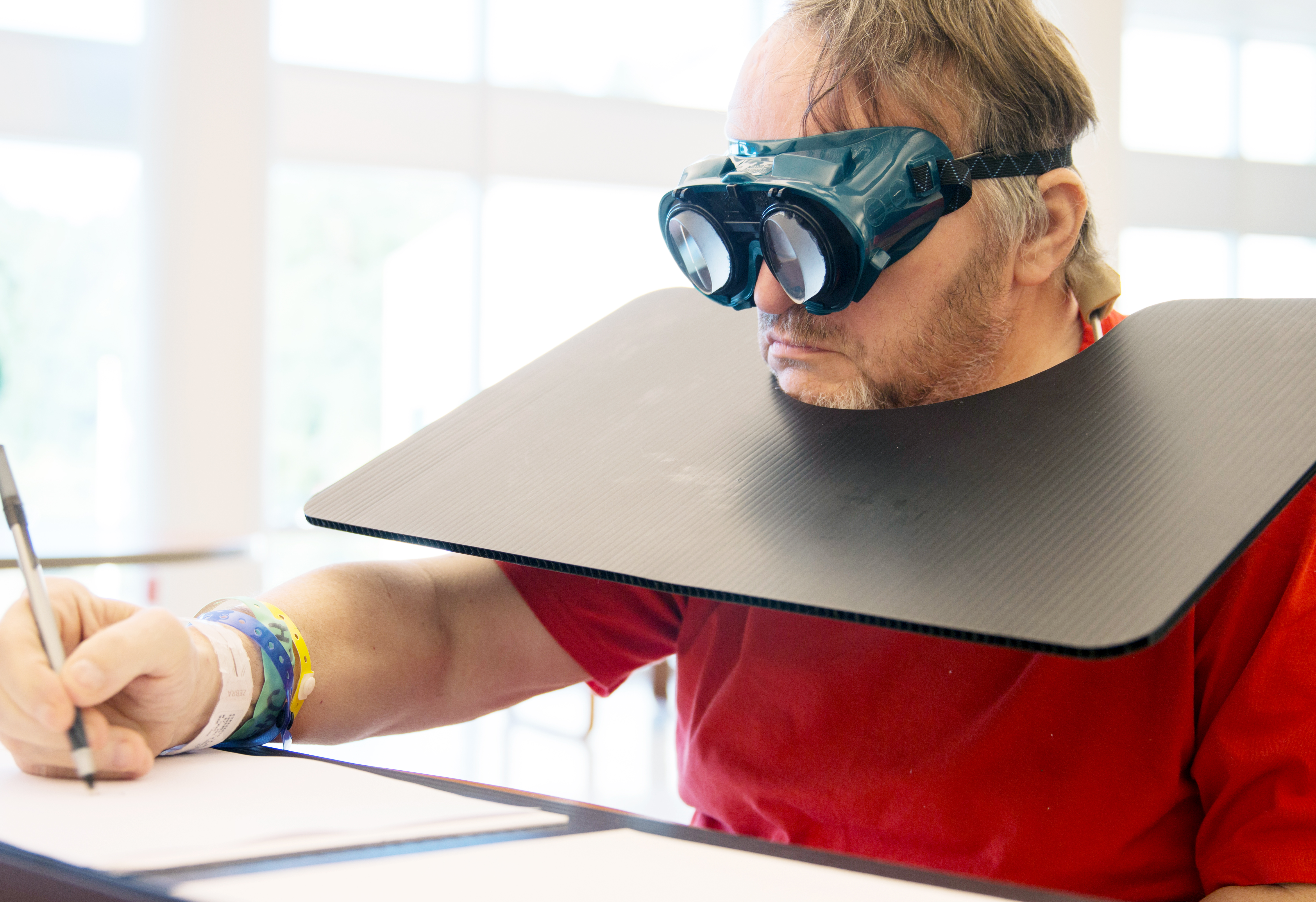 Man is wearing prism adaptation lenses and writing on a piece of paper