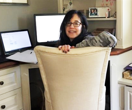 Lauri Wactlar, sitting on a white chair, next to her computer 