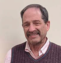 Man with white shirt and grey sweater vest with a mustache