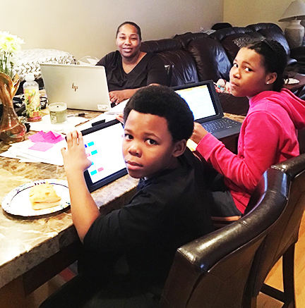 Natasha Johnson working from home with her kids at a table. 