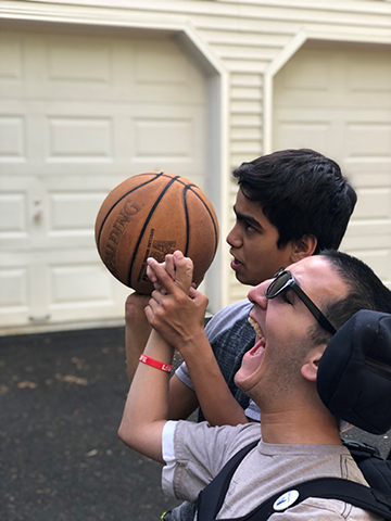 Daniel helping Jacob shoot a basketball
