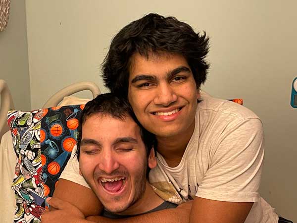 Two brothers smiling and hugging together. 