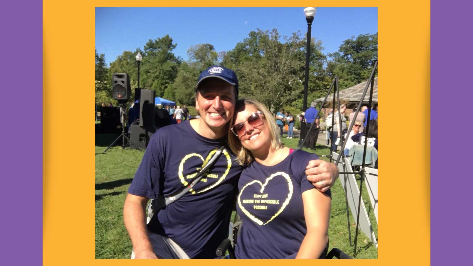 A man and a woman smiling for the camera at a park event wearing blue t-shirts