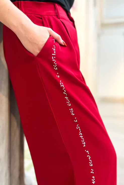 graphic shows a woman from the waist down wearing a pair of red pants that have braille design going down side of leg.