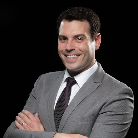 White male in a grey suite and black tie