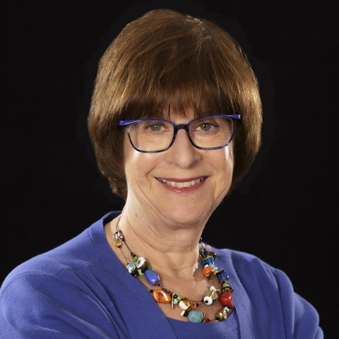 Lady wearing a purple blouse, necklace and eyeglasses