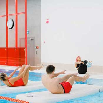man and two women exercising near pool