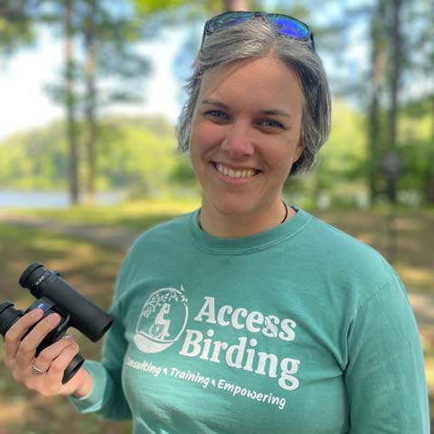 Woman with green shirt at a park holding a binoculars