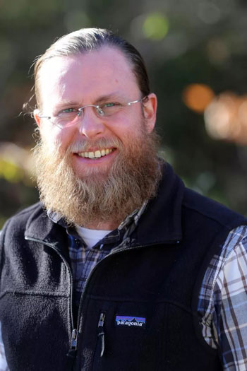 Man with eyeglasses and vest outside in the wilderness