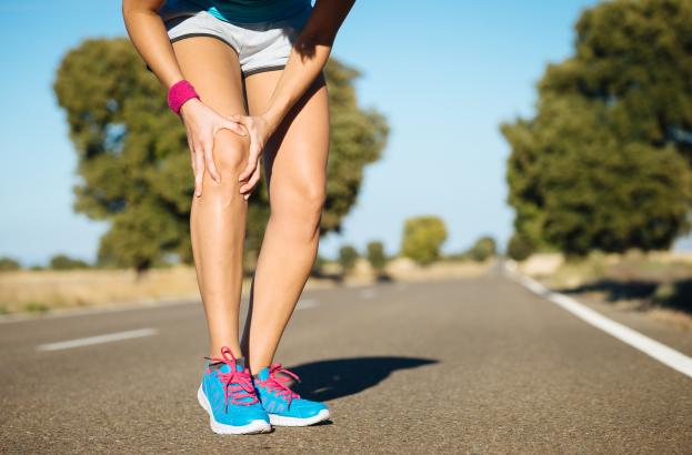 Image showing a person's legs holding their knee in pain.