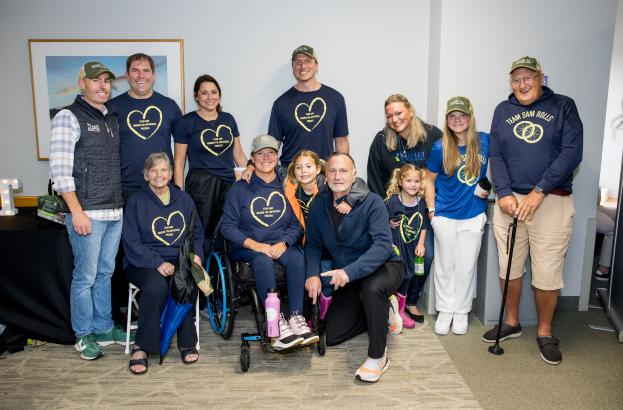 Group of supporters wearing matching team shirts and hats gathered for a Kessler Foundation peer-to-peer fundraising event, promoting community involvement and disability research. 