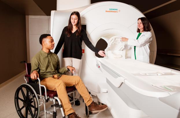 Patient and researchers standing by an MRI scanner