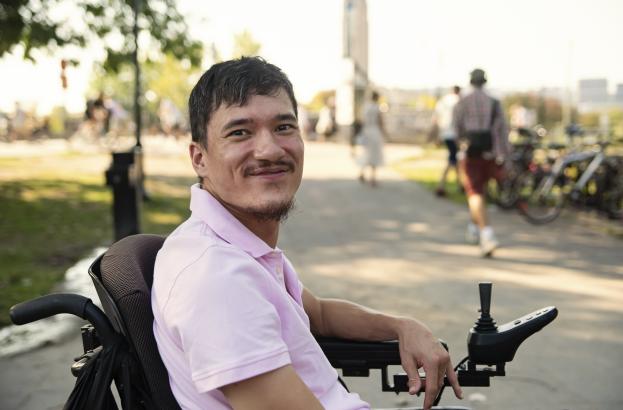 Man using a power wheelchair sits in a public park