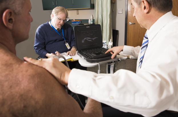 Clinician performs an ultrasound scan on a research participant’s shoulder, with the imaging screen displaying the shoulder joint during a study on shoulder pain in wheelchair users.
