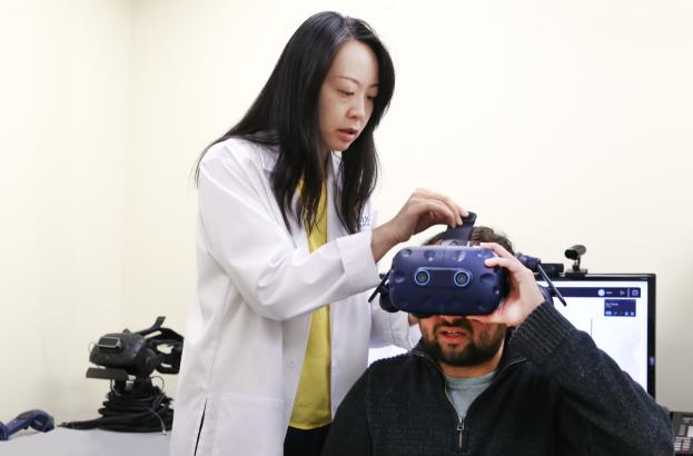 Researcher helping put AI goggles on man sitting next to her