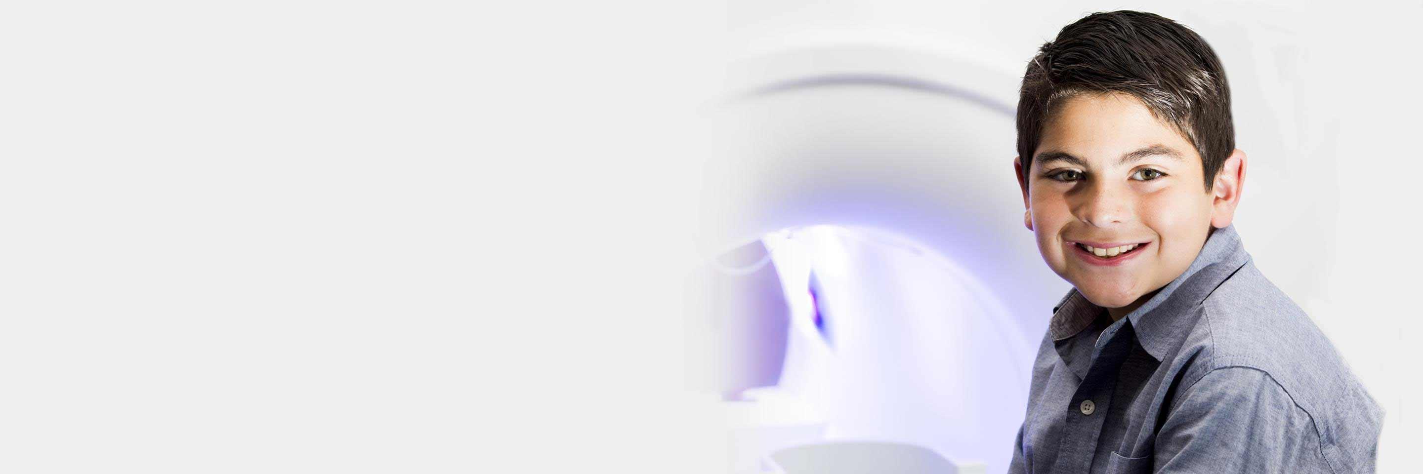 Boy sitting on bed of mock scanner