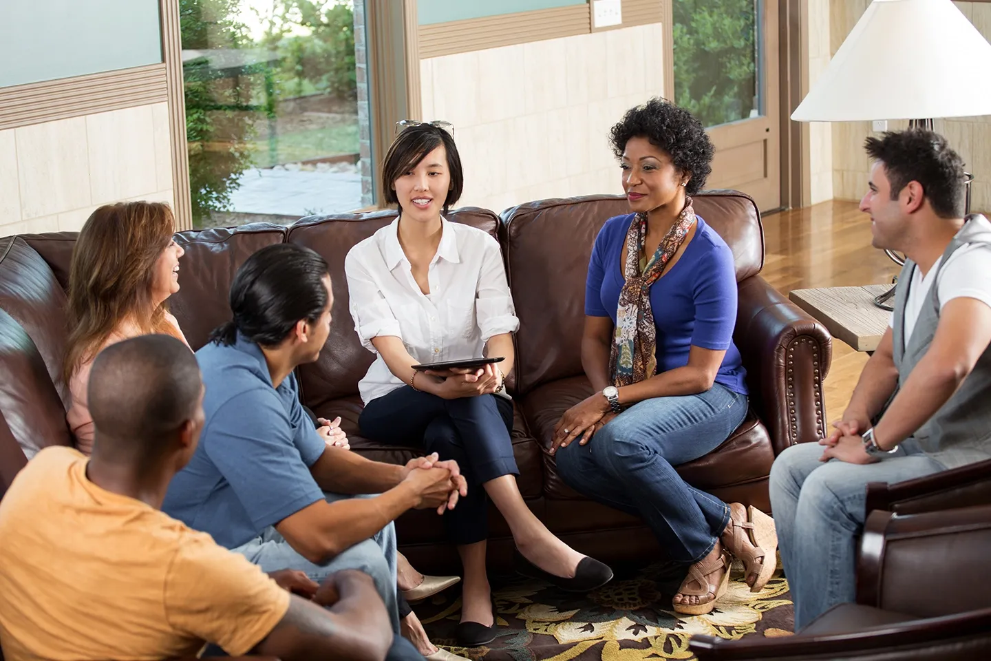 Several people of different ethnicities sit together having a group discussion.