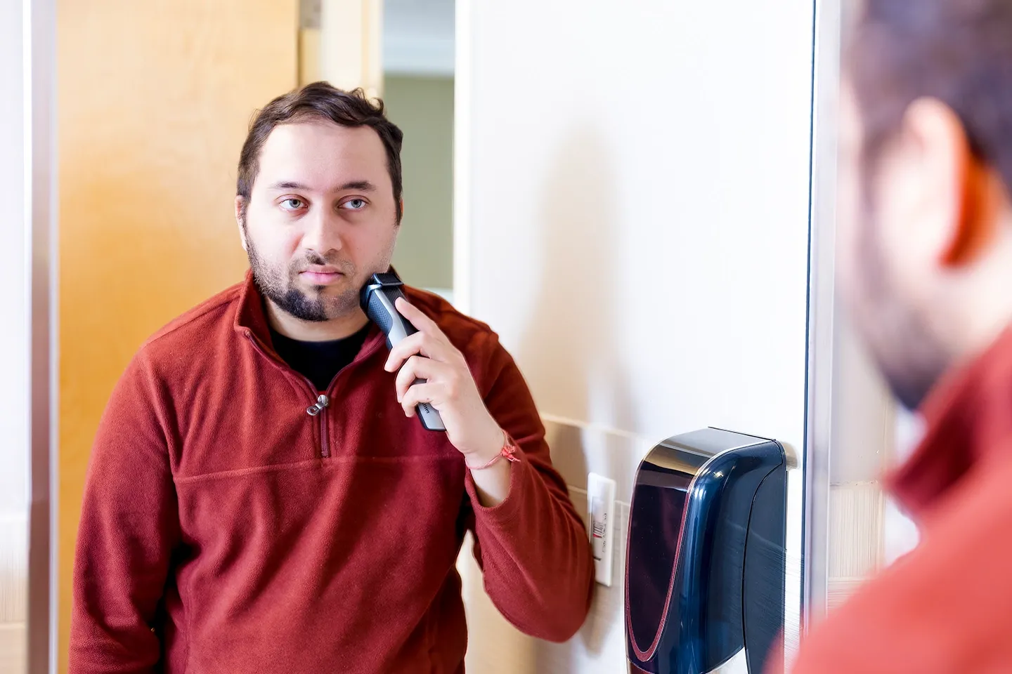 Man with spatial neglect looking in a mirror and shaving only one side of his beard.