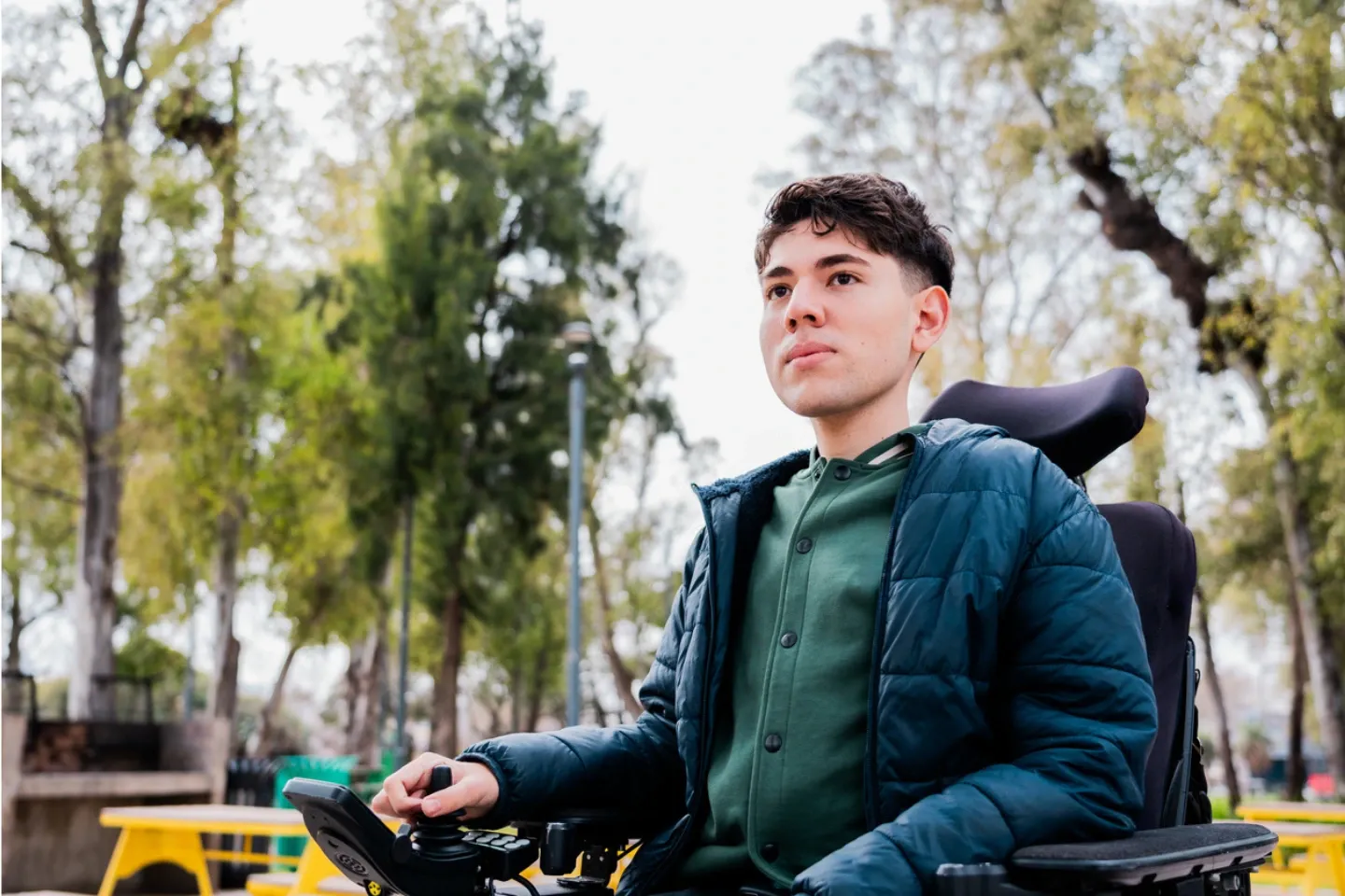 a man seating in a wheelchair with trees behind him