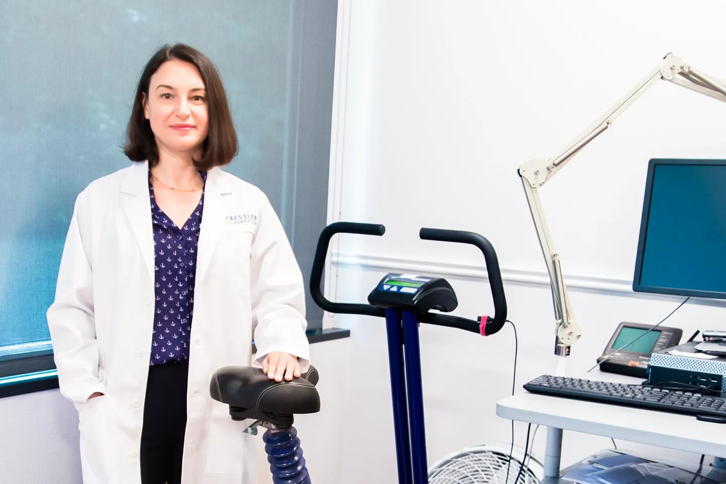 Center for Stroke Rehabilitation researcher Olga Boukrina, PhD, stands beside exercise bike and data-gathering equipment used to study post-stroke aphasia.