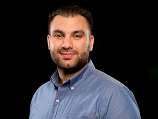 male senior research scientist with dark hair and wearing a blue button down shirt.