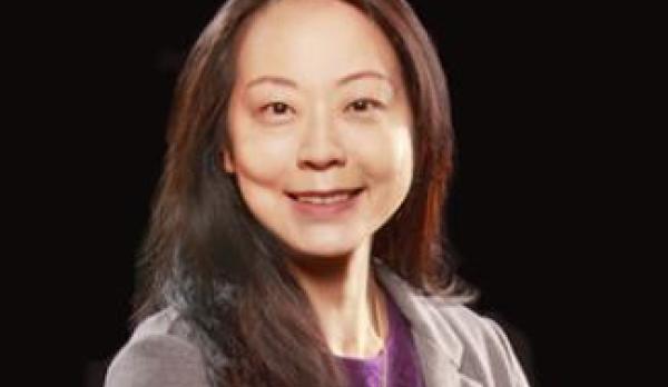 Director wearing purple shirt and grey blouse smiling for the camera