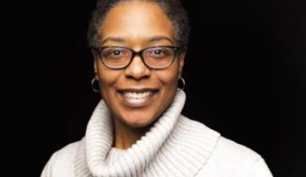 Director wearing a white blouse and glasses smiling for the camera