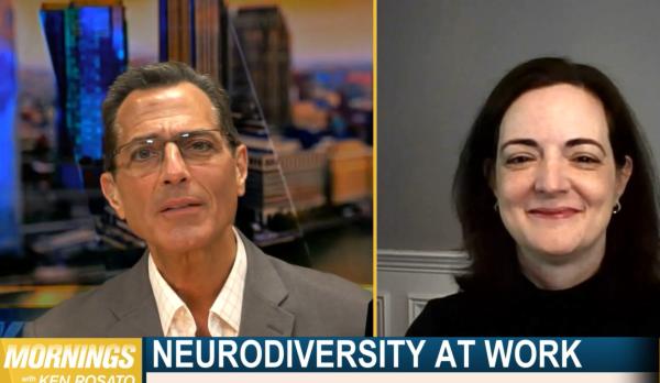 A man in a gray suit and glasses is interviewing a brunette woman wearing a black turtleneck about neurodiversity at work.