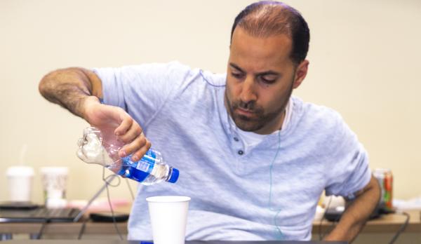 Man is pouring water into a cup after receiving spinal stimulation.